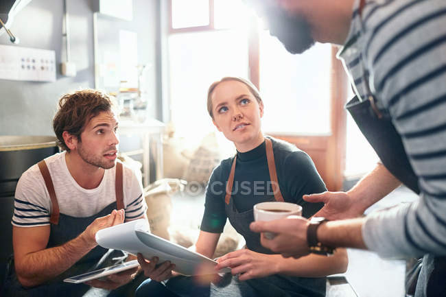 Coffee roasters with clipboard talking and tasting coffee in meeting — Stock Photo