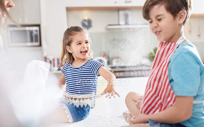 Sister throwing flower at brother, baking in kitchen — Stock Photo