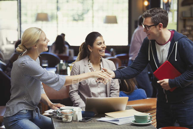 Gente creativa de negocios saludando, apretón de manos en la cafetería - foto de stock