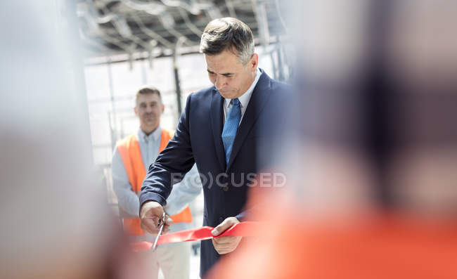 Businessman cutting ribbon at new construction site ceremony — Stock Photo