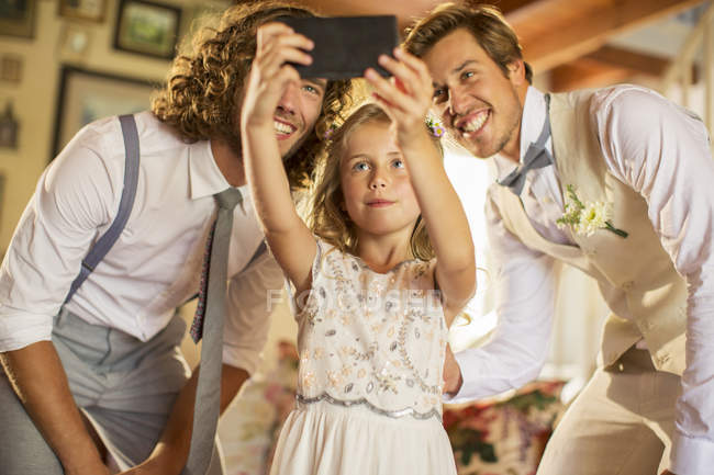 Bridegroom, best man and bridesmaid photographing self in domestic room — Stock Photo