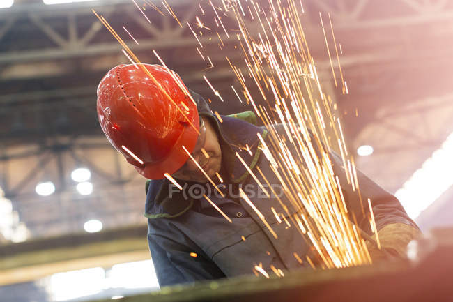 Сварщик с помощью сварочной горелки с искрами на сталелитейном заводе — стоковое фото