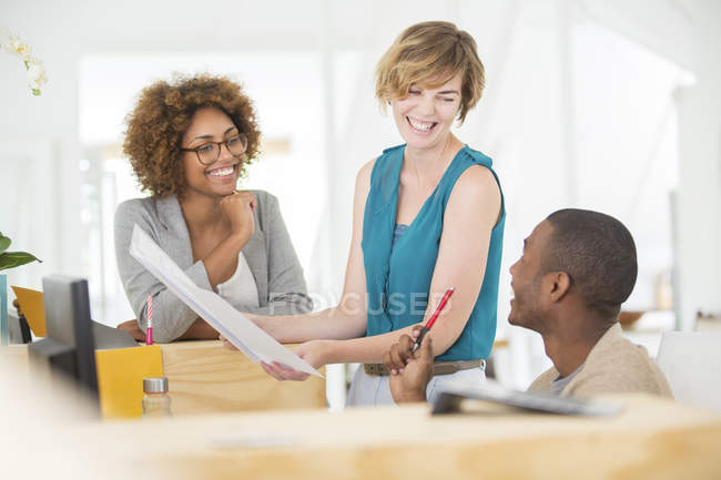 Kollegen reden und lächeln im Büro, halten Dokumente in der Hand — Stockfoto