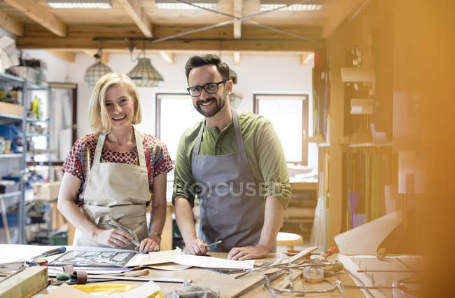 Artistas de vidrieras sonrientes trabajando en estudio - foto de stock