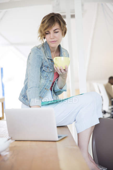 Trabalhador de escritório com café usando laptop no escritório moderno — Fotografia de Stock