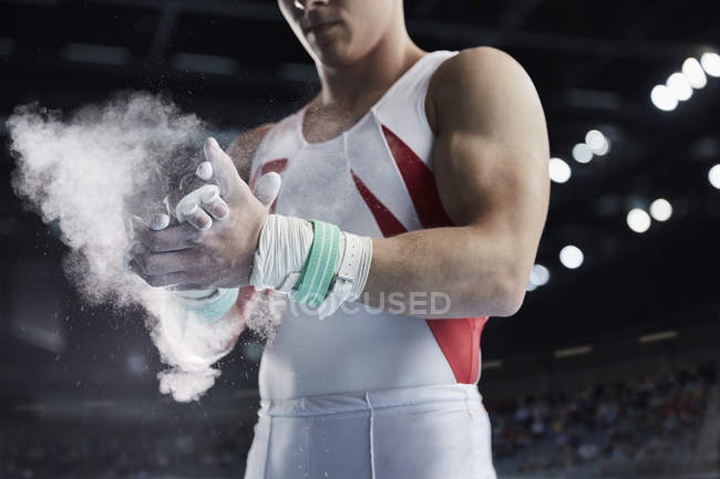 Male gymnast applying chalk powder to hands — Stock Photo