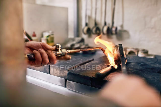 Jeweler heating metal with torch in workshop — Stock Photo