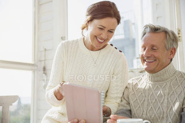 Sorrindo casal maduro usando tablet digital no alpendre ensolarado — Fotografia de Stock