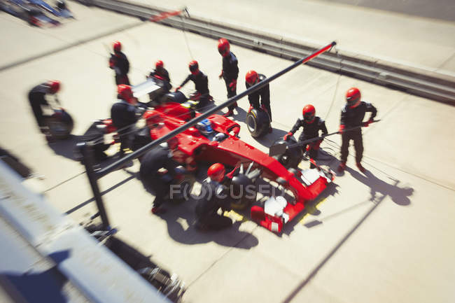 Pit crew replacing tires on formula one race car in pit lane — Stock Photo