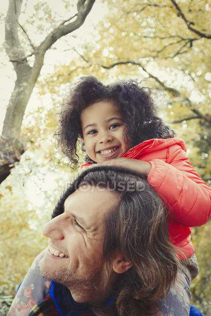 Portrait souriant père père portant fille sur les épaules dans le parc d'automne — Photo de stock