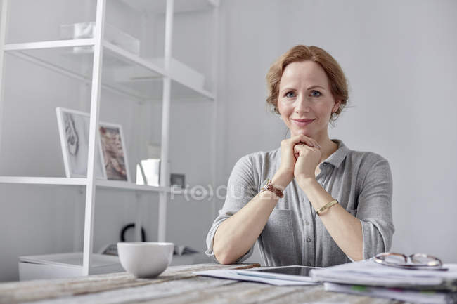 Retrato sonriente, mujer de negocios segura de usar tableta digital y beber té en la oficina - foto de stock