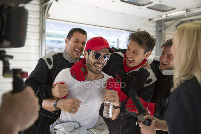 Piloto de Fórmula 1 y equipo celebrando victoria en garaje de reparación - foto de stock