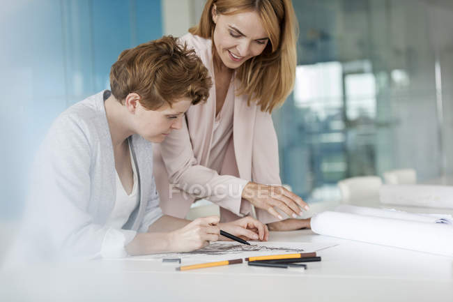 Female designers reviewing sketch drawings in conference room meeting — Stock Photo
