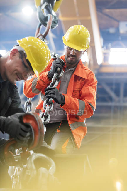 Steel workers with crane hook in factory — Stock Photo