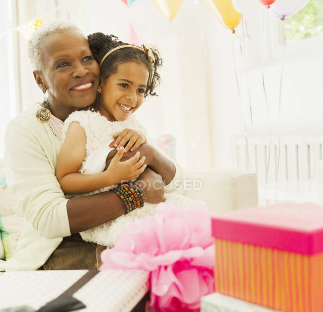 Affectionate grandmother and granddaughter hugging at birthday party — Stock Photo