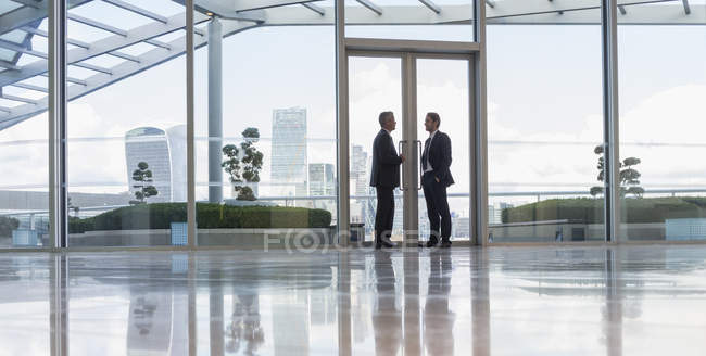 Бизнесмены разговаривают в дверях городских высотных зданий — стоковое фото