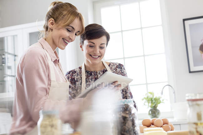 Sorridente ristoratori femminili utilizzando tablet digitale, cottura in cucina — Foto stock