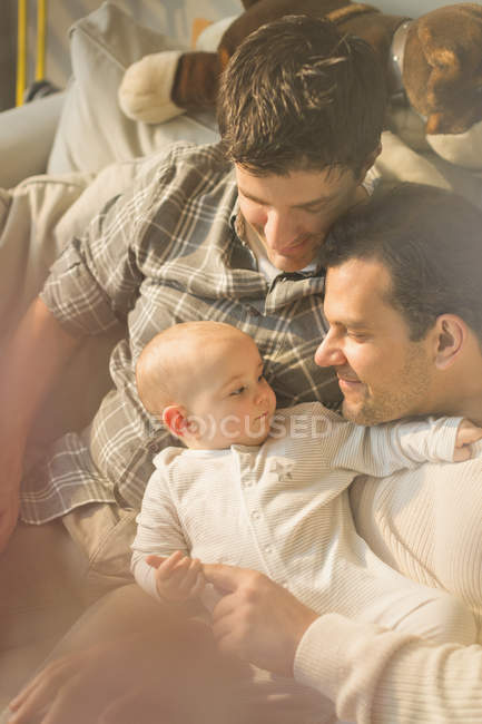 Affectionate male gay parents and son cuddling — Stock Photo