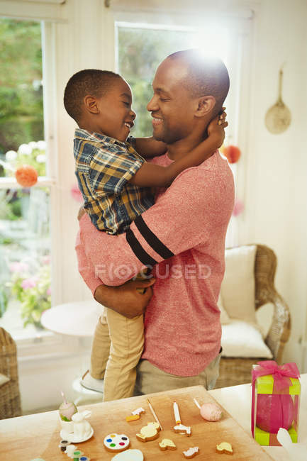 Padre e hijo cariñosos abrazándose al lado de las decoraciones de Pascua - foto de stock