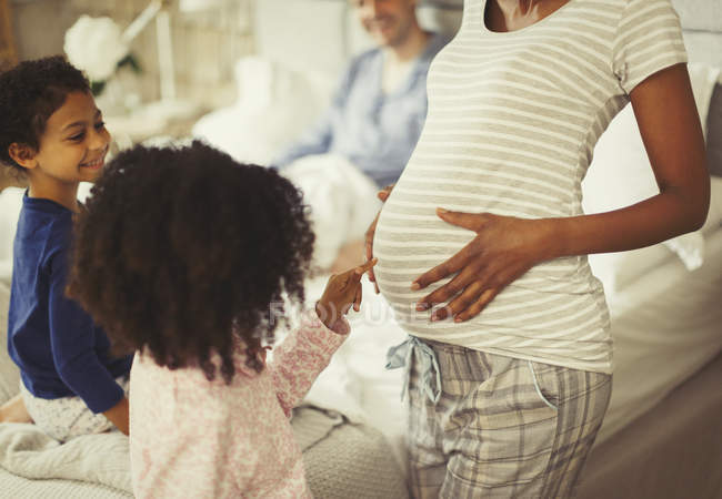 Curiosa hija tocando el estómago de la madre embarazada - foto de stock
