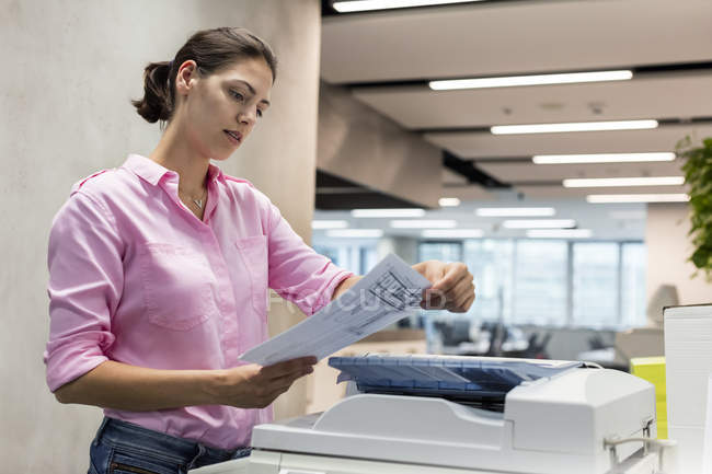 Businesswoman using photocopier in office — Stock Photo