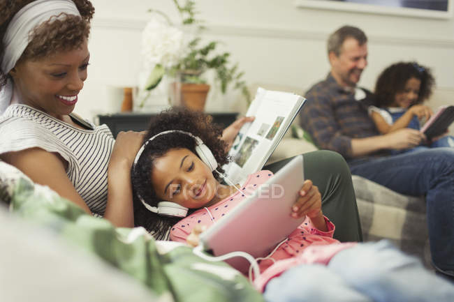 Mutter kuschelt Tochter mit Kopfhörer mit digitalem Tablet — Stockfoto