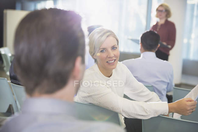 Улыбающаяся деловая женщина разговаривает с бизнесменом в аудитории конференции — стоковое фото