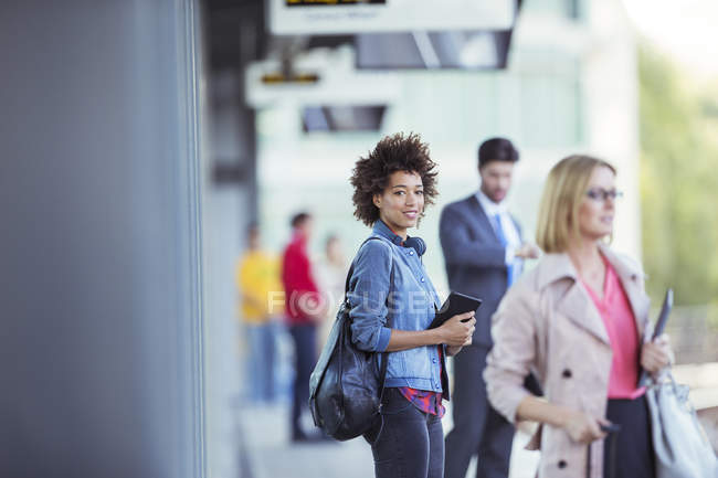 Женщина держит цифровой планшет и ждет поезд на станции — стоковое фото