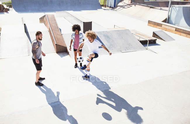 Männliche Freunde spielen Fußball im sonnigen Skatepark — Stockfoto