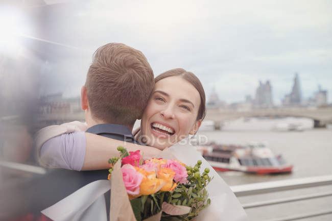Glückliche, dankbare Frau erhält Blumenstrauß, umarmt Freund am städtischen Ufer — Stockfoto