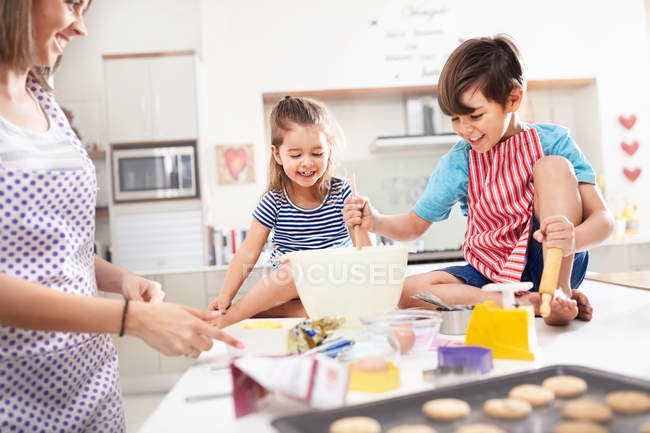 Mutter und Kinder backen Plätzchen in Küche — Stockfoto
