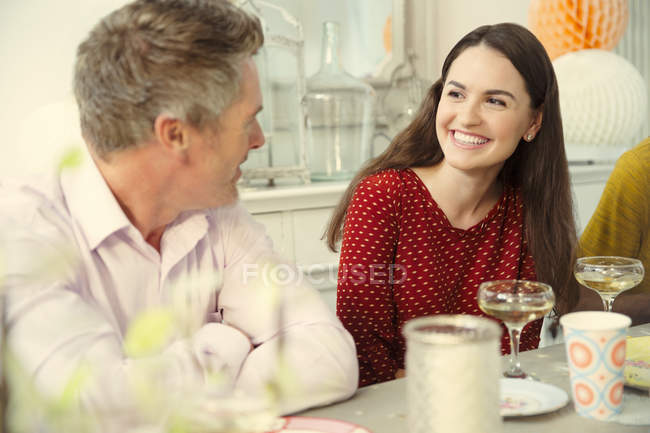Smiling couple talking and drinking champagne at party table — Stock Photo