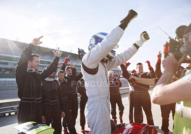 Equipe de Fórmula 1 e torcida do piloto, comemorando a vitória na pista de esportes — Fotografia de Stock