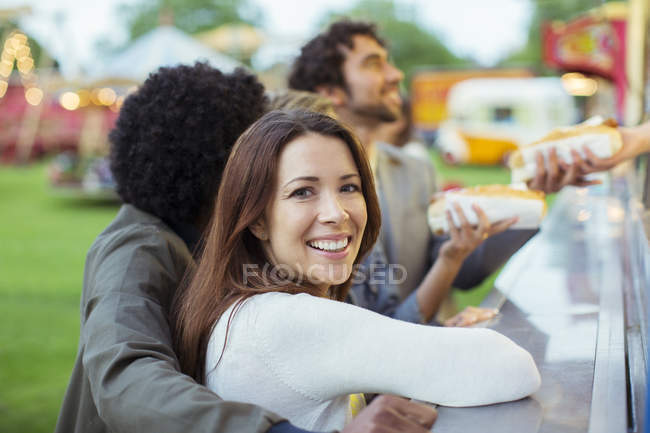 Gente comprando perritos calientes en puestos de comida en el parque de atracciones - foto de stock