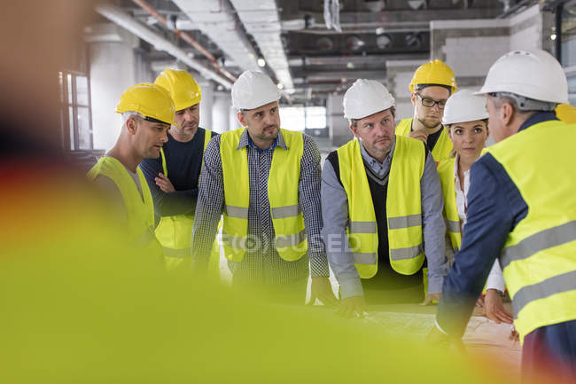 Foreman conversando com engenheiros e trabalhadores da construção civil no canteiro de obras — Fotografia de Stock