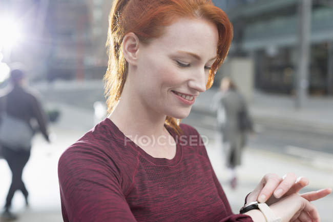 Крупним планом усміхнена жінка бігунка перевіряє розумний годинник — стокове фото