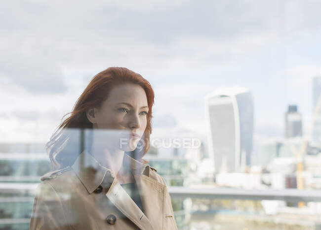 Empresária confiante com cabelos vermelhos na varanda urbana com vista para a cidade — Fotografia de Stock