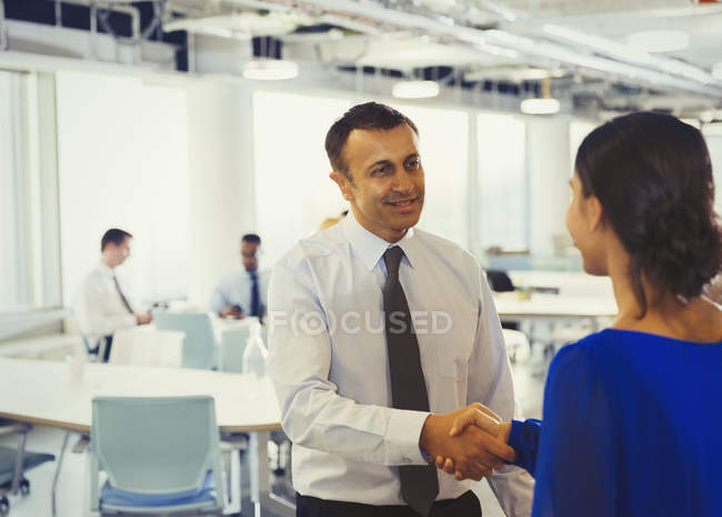 Бизнесмен пожимает руку деловой женщине в офисе — стоковое фото