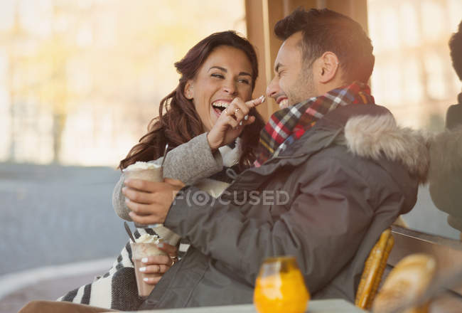 Jeune couple ludique avec milkshake au café trottoir — Photo de stock