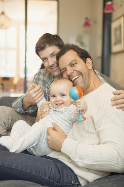 Portrait male gay parents and baby son with rattle — Stock Photo