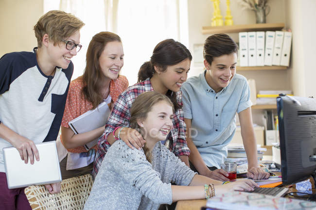Grupo de adolescentes que utilizan juntos el ordenador en la habitación - foto de stock