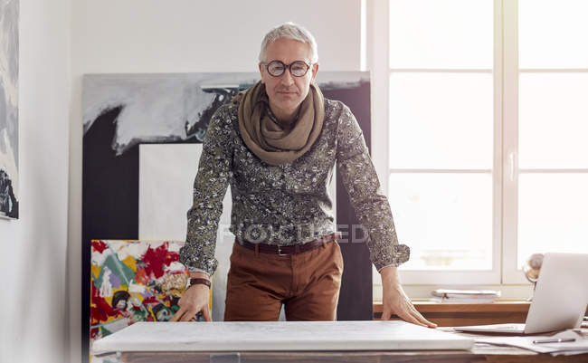 Portrait confident male photographer standing over canvas in art studio — Stock Photo