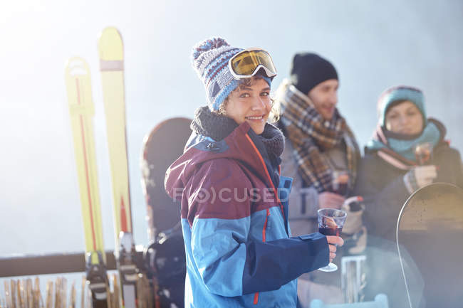 Portrait de skieuse souriante buvant un cocktail sur le balcon avec des amis apres-ski — Photo de stock