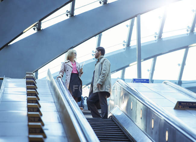 Business people riding escalator — Stock Photo