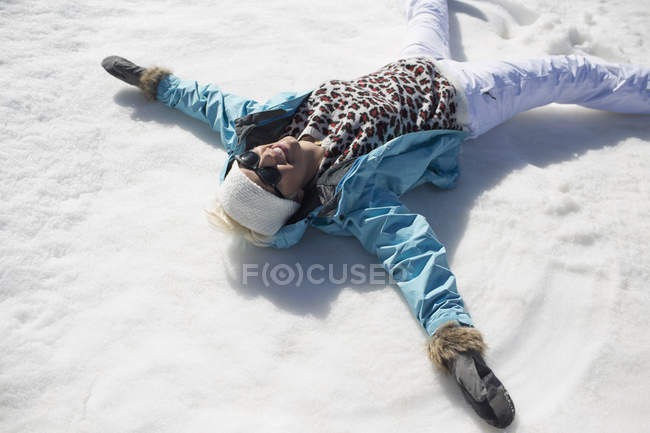 Femme heureuse faisant des anges de neige — Photo de stock