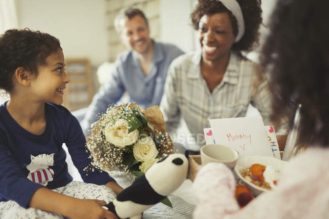 Daughters serving breakfast and flowers to mother in bed on Mothers Day — Stock Photo