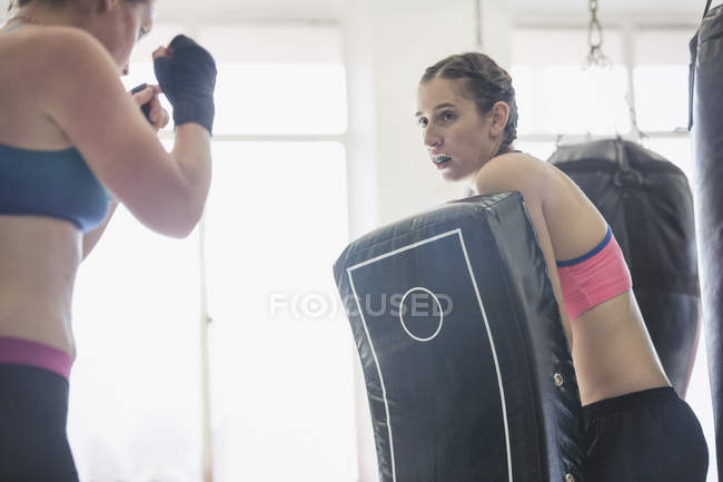 Mulheres praticando kickboxing com estofamento no ginásio — Fotografia de Stock