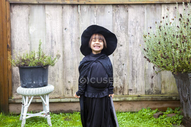 Portrait enthusiastic girl wearing witch costume in garden — Stock Photo