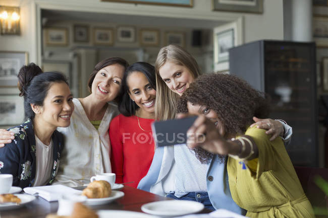 Mujeres sonrientes amigas tomando selfie en la mesa del restaurante - foto de stock