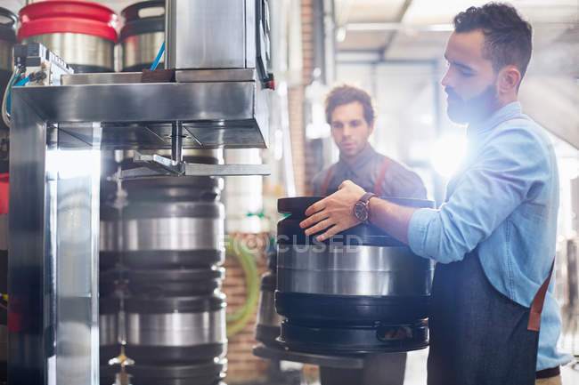 Male brewers filling kegs in brewery — Stock Photo